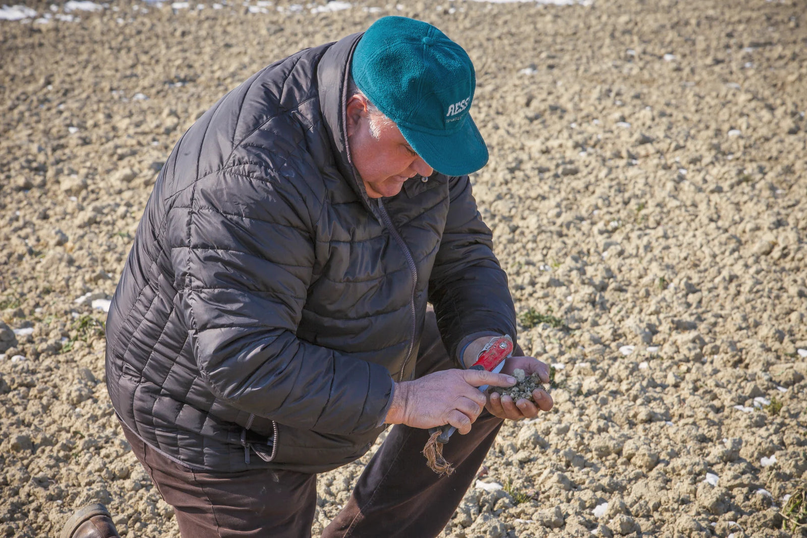 Un uomo inginocchiato che controlla il terreno del campo