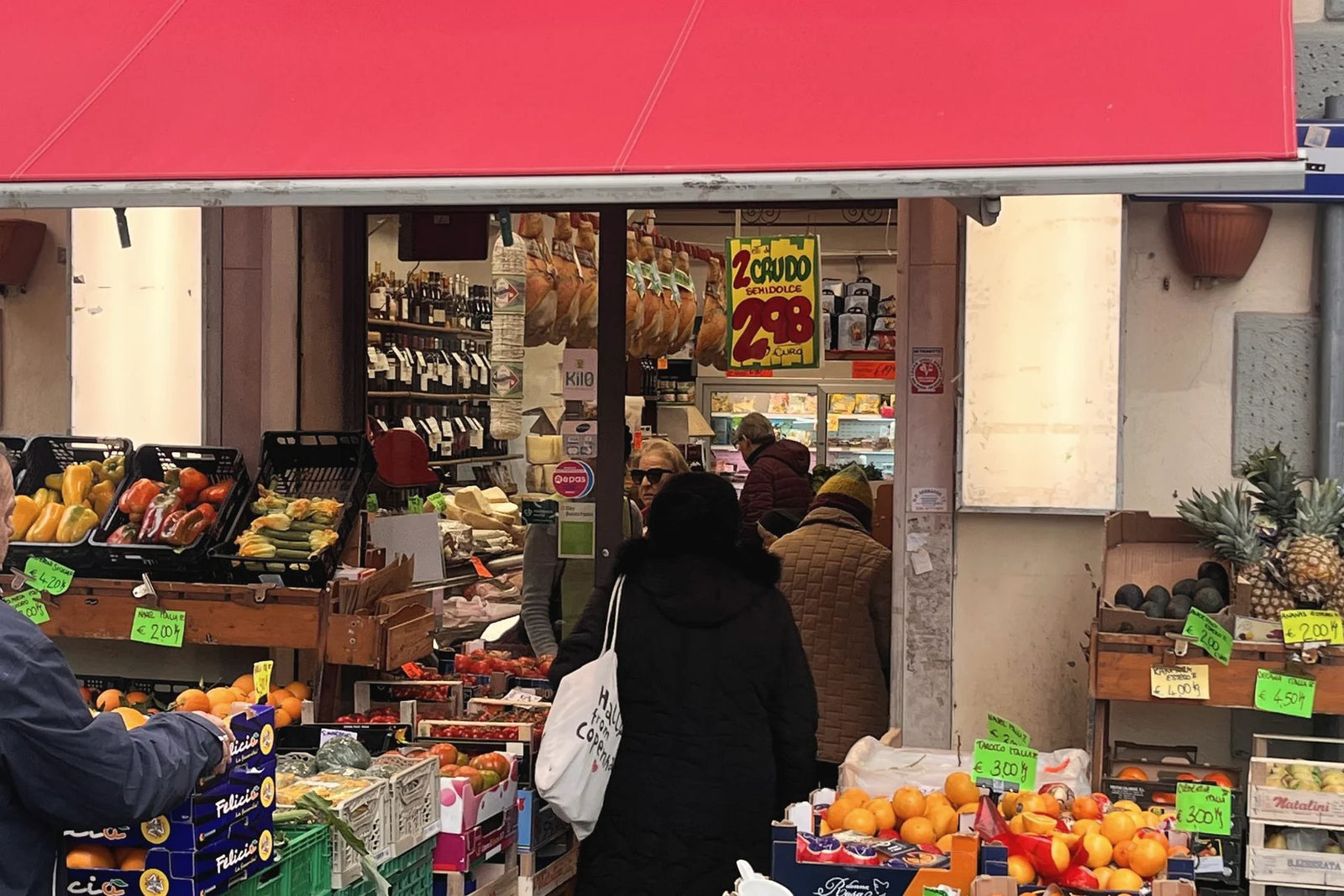 L'ingresso in via Demi con il banco di frutta e verdura e i clienti