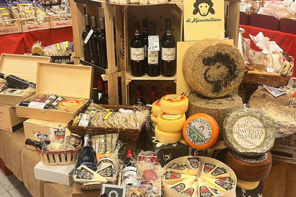 Forme di formaggio, confezioni regalo e vini in esposizione in bottega