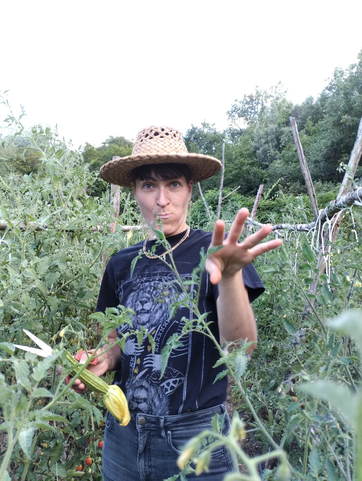 Una donna con il cappello di paglia in mezzo alle piante di pomodoro