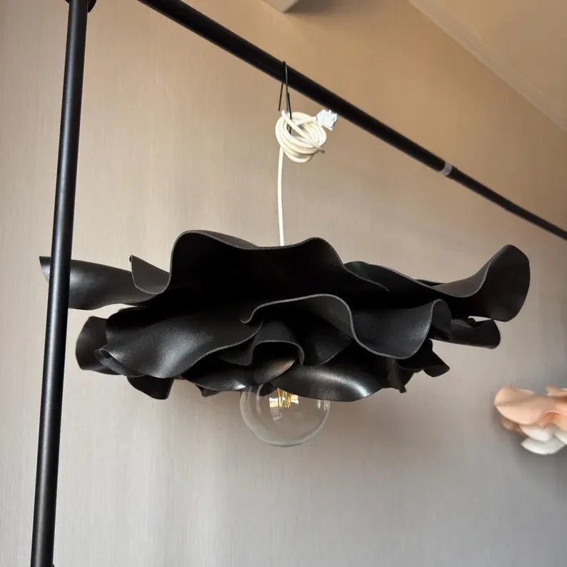 Un lampadario nero a petali tenuto da una mano prima di essere appeso