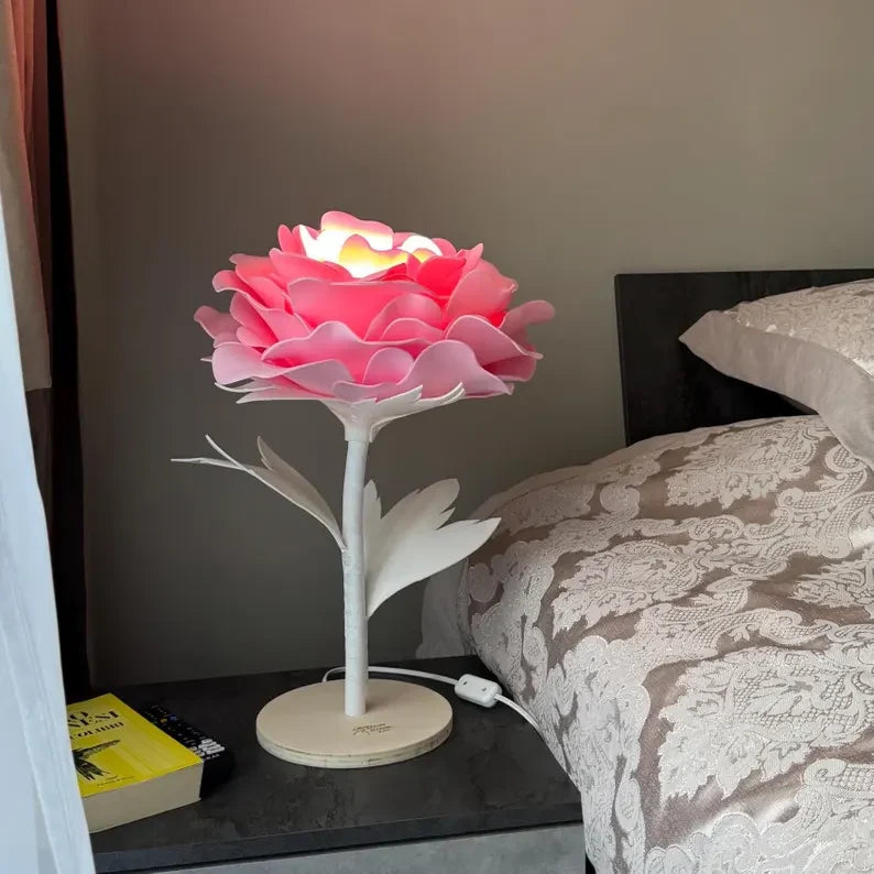 Lampada a forma di rosa rosa accesa sul comodino di una camera