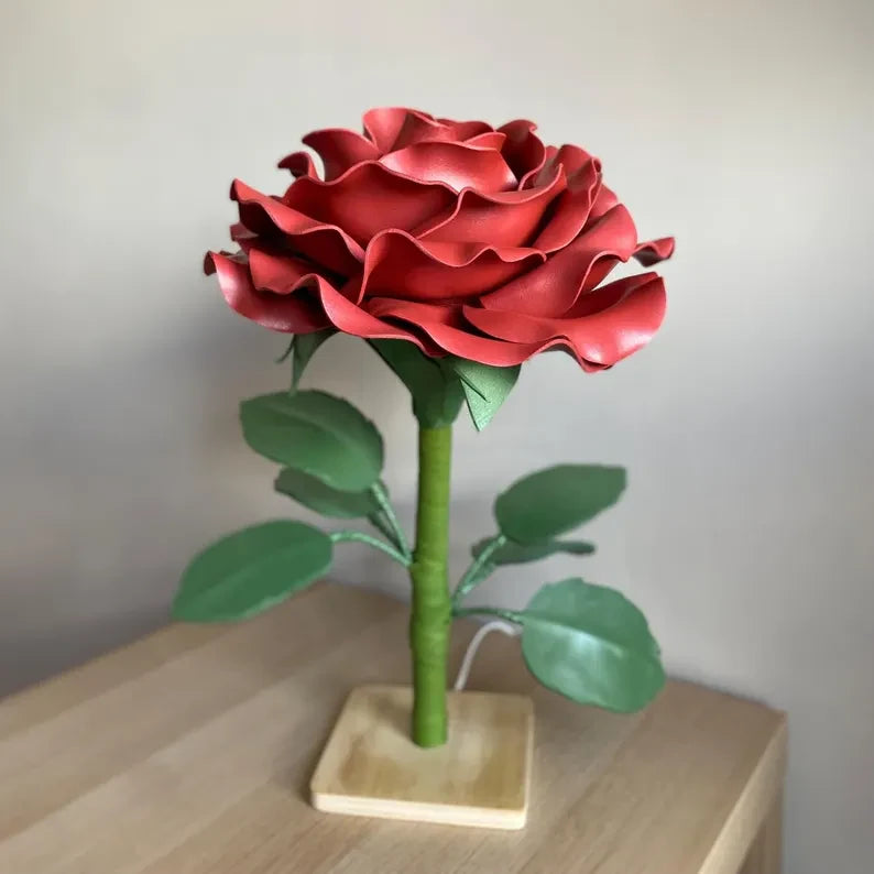Lampada a forma di rosa rossa con gambo e foglie su base di legno