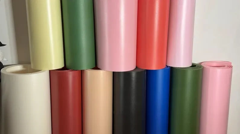 Rotoli di foglio colorato appoggiati in fila su un banco