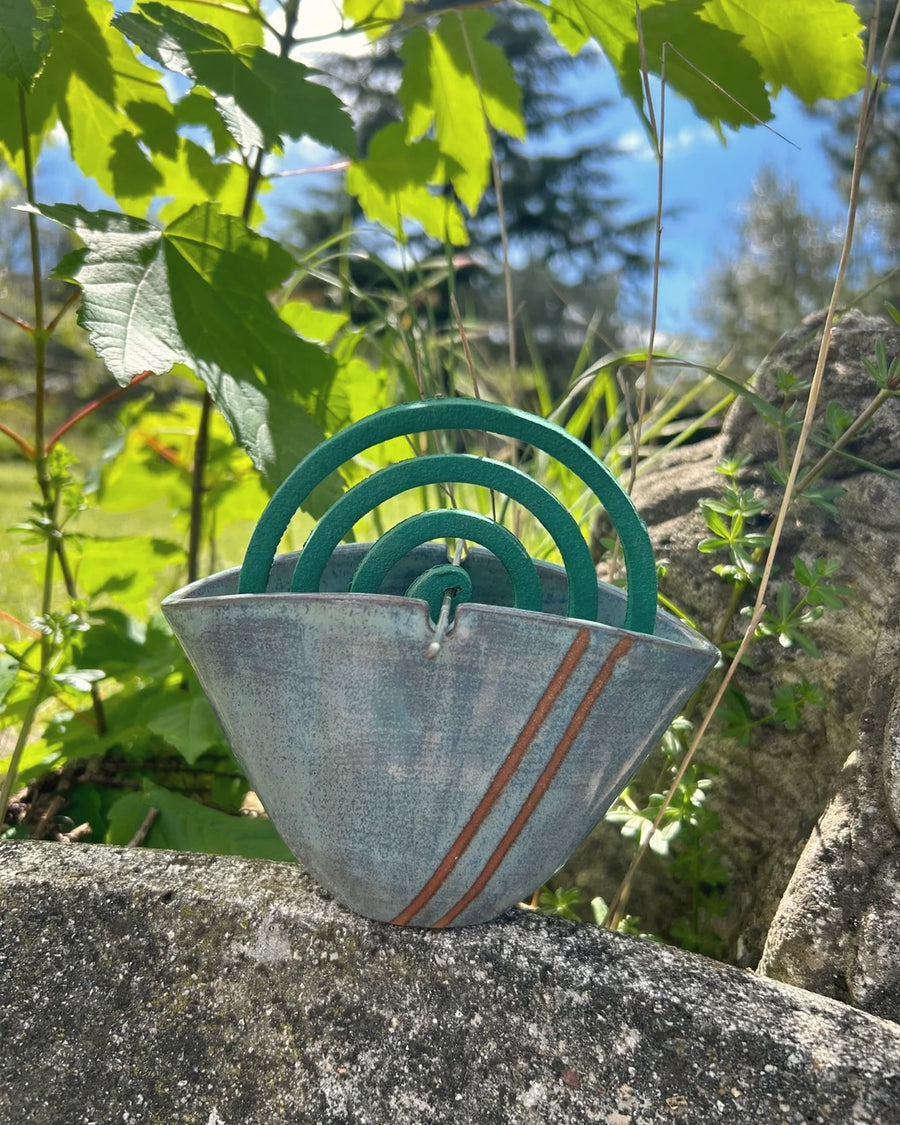 Portazampirone in ceramica smaltata appoggiato su una pietra, nel verde del giardino