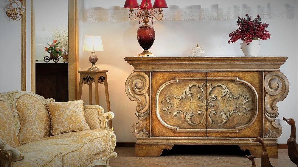 Credenza intagliata e dorata della linea Antica Firenze, accanto a un divano damascato