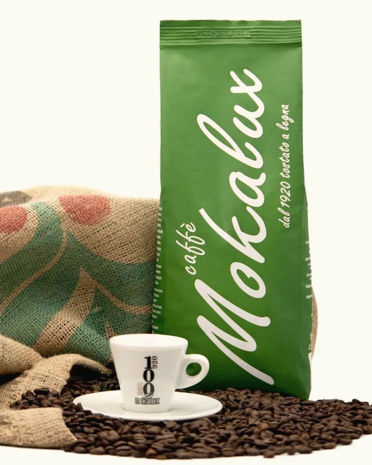 Busta verde di caffè in grani con tazzina e chicchi
