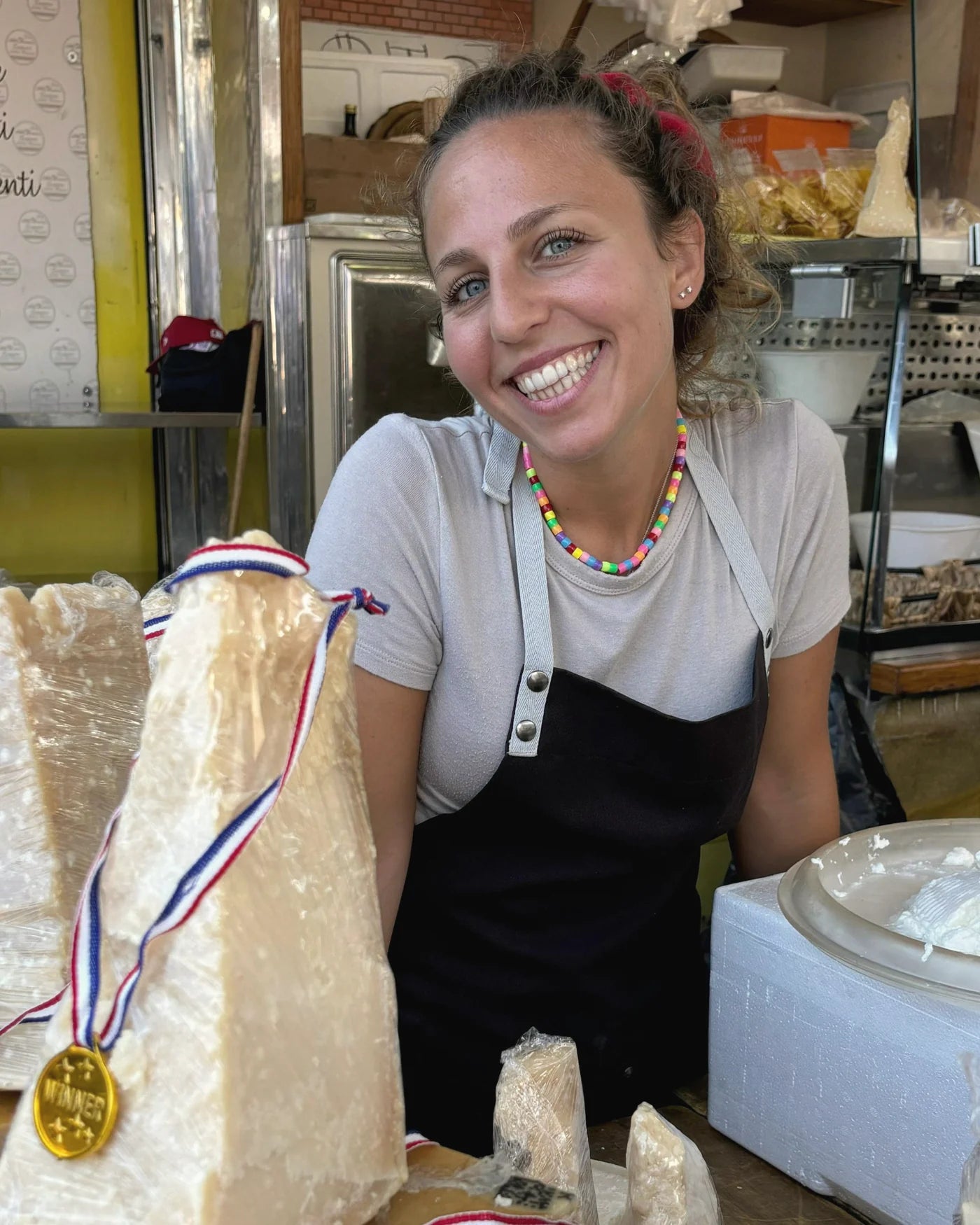 Una addetta al banco con una grande forma di formaggio premiata