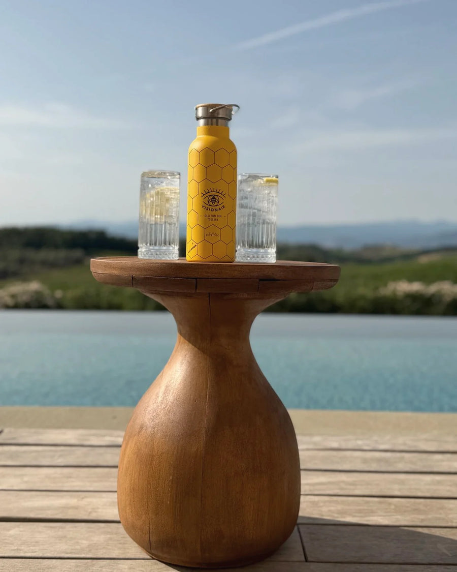 Una borraccia e due bicchieri su un tavolino di legno, la piscina e le colline dietro