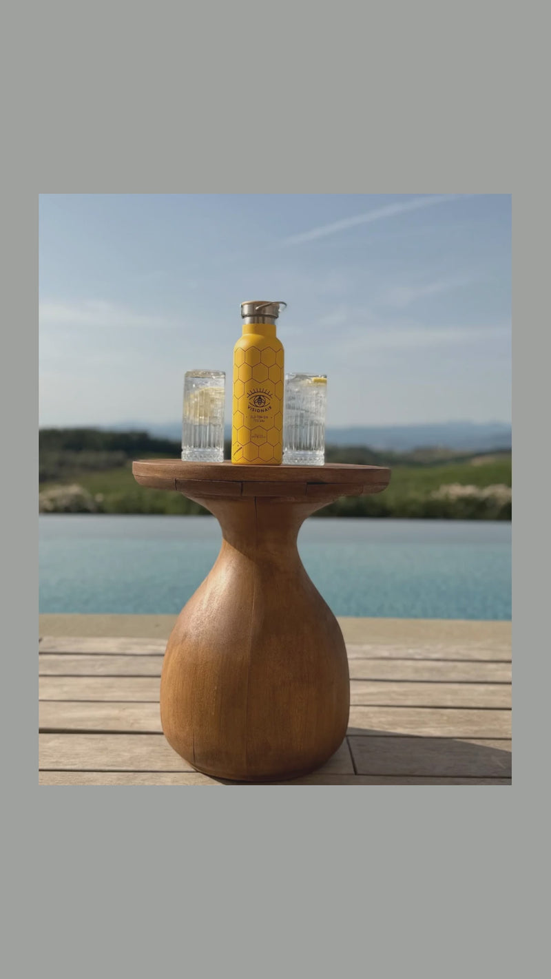 Le fotografie di Visionair Gin in sequenza: la borraccia gialla sul tavolo di legno, il brindisi, il muretto sul mare e la fila delle borracce.